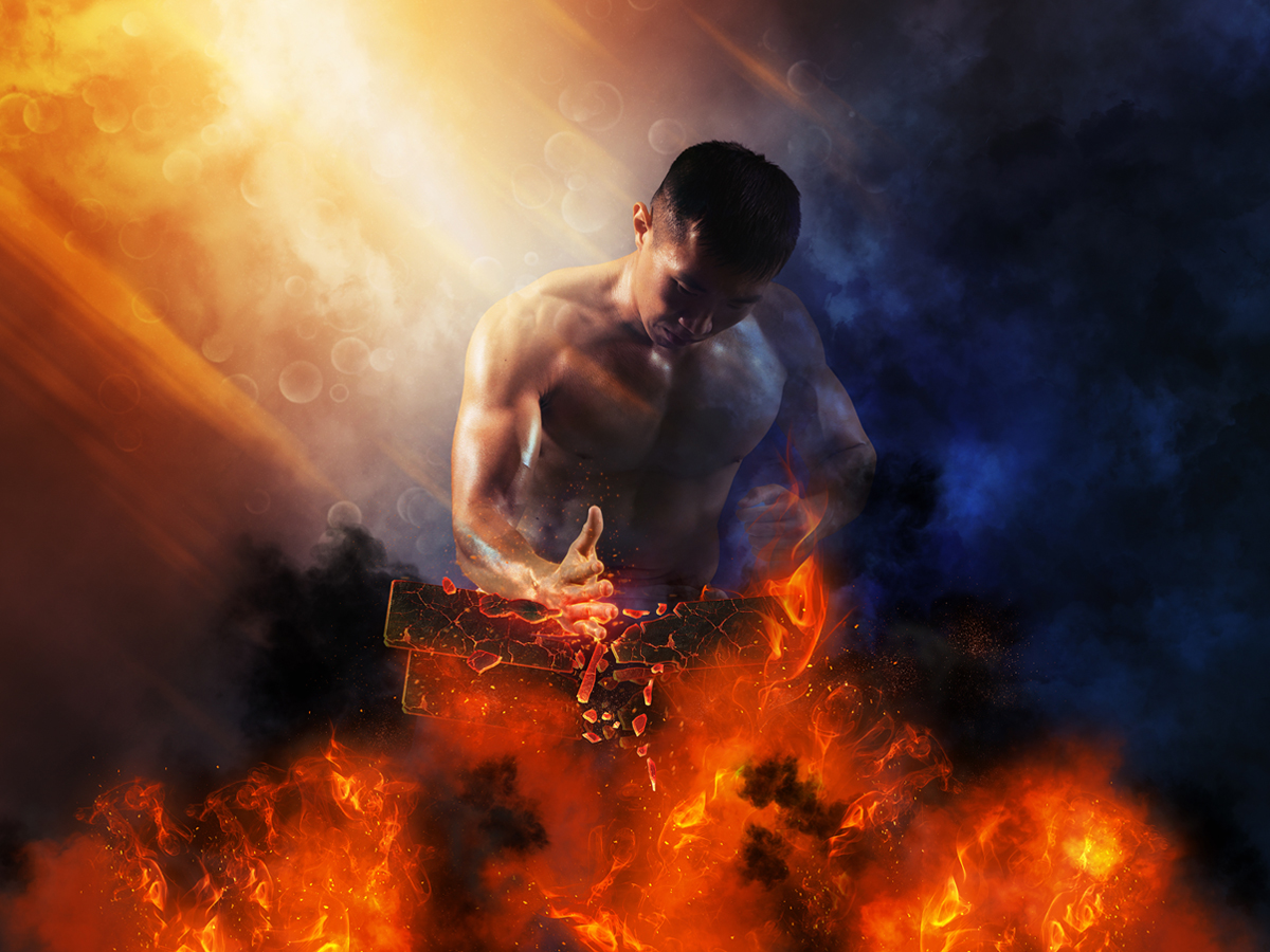 Besiege deine Dämonen Mann zerschlägt brennende Backsteine mit seiner Hand